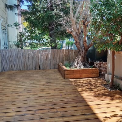 דק עץ עם עץ גדול וערוגה מוגבהת