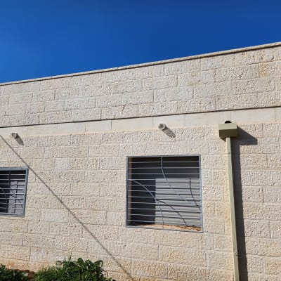 שני חלונות עם סורגים על קיר אבן חיצוני