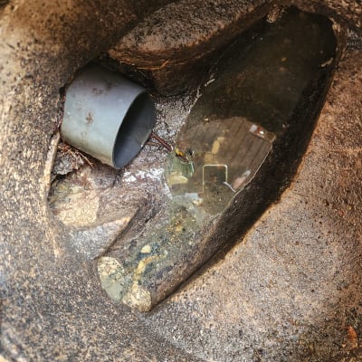 צינור פלסטיק אפור בתוך חור עם מים