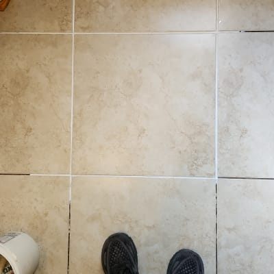 רצפת אריחים, דלי עם כלים, רגליים בנעלי עבודה