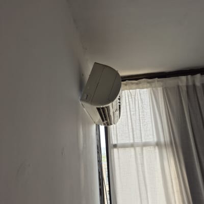 מזגן מותקן על קיר ליד חלון עם וילון