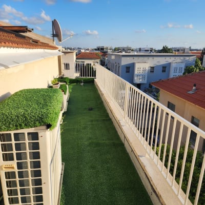 מעקה לבן לאורך מרפסת עם דשא סינתטי
