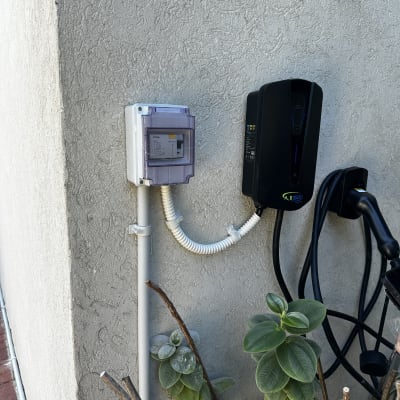 תמונה של לוח חשמל ומטען לרכב חשמלי על קיר חיצוני