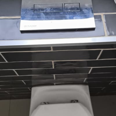 לחצן הדחה על קיר אריחים בשירותים