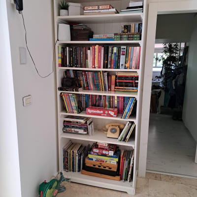 מדף ספרים עם ספרים, משחקים וטלפון ישן