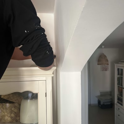 חשמלאי עובד על חיווט בקיר ליד ארון