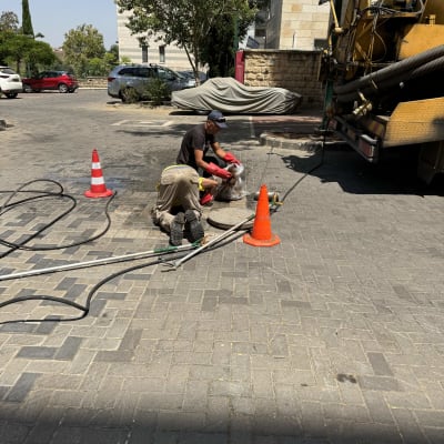 משאית ואקום עם צינורות ועובדים בכביש