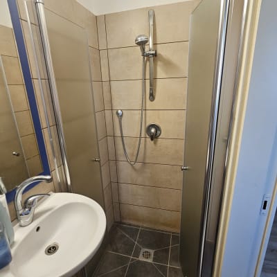 מקלחת עם ראש מקלחת, דלתות זכוכית וברז.