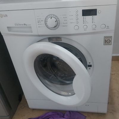 מכונת כביסה עם מגבת סגולה על הרצפה