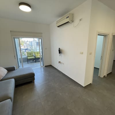 סלון עם קירות לבנים ורצפת אריחים אפורה