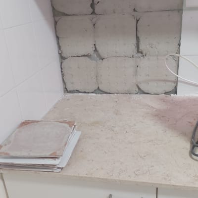 קיר עם אריחים לא גמורים ומדף עם כלים