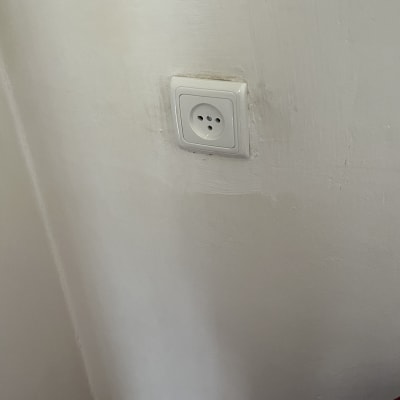 שקע חשמלי בקיר לבן עם רצפה עץ