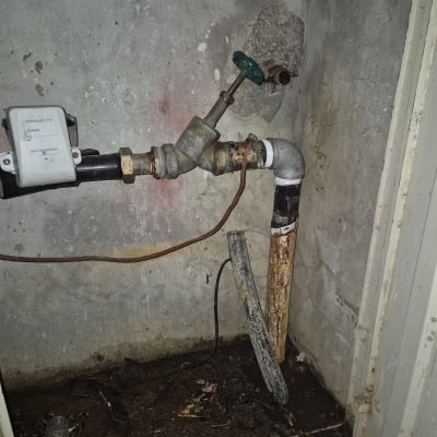 צינור חלוד עם ברז ירוק על קיר בטון