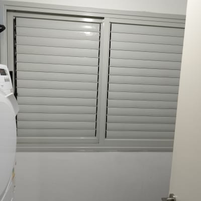 תריסים אפורים סגורים על חלון קיר לבן