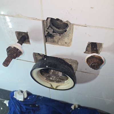 צנרת חלודה עם חור בקיר ואריחים שבורים