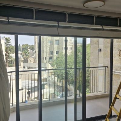 תריסים פתוחים עם אדם וסולם ליד חלון גדול