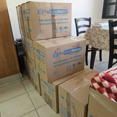קופסאות קרטון לאריזה בחדר עם שולחן וכיסאות