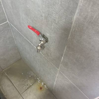 ברז עם ידית אדומה על קיר אריחים אפור