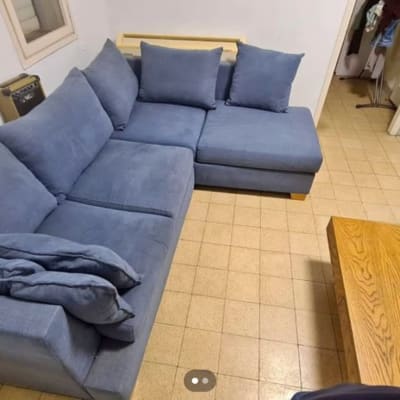 ספה פינתית כחולה עם כריות על רצפת אריחים