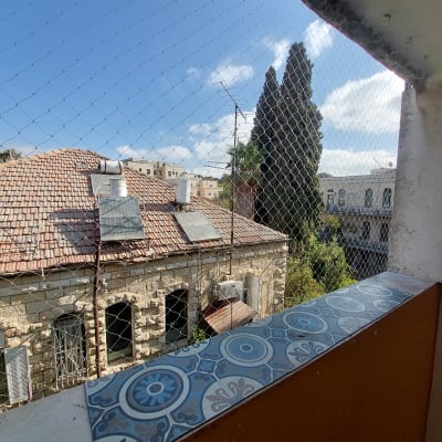 רשת יונים מותקנת על מרפסת עם נוף לגגות