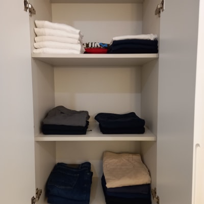 בגדים מקופלים בארון לבן עם שלושה מדפים