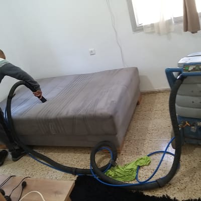 אדם מנקה מזרן עם שואב אבק תעשייתי