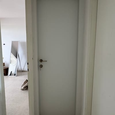 דלת לבנה במסדרון עם מראה ברקע