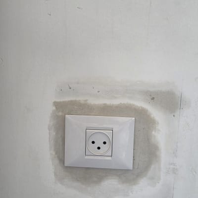 שקע חשמלי בקיר עם סימני תיקון סביבו