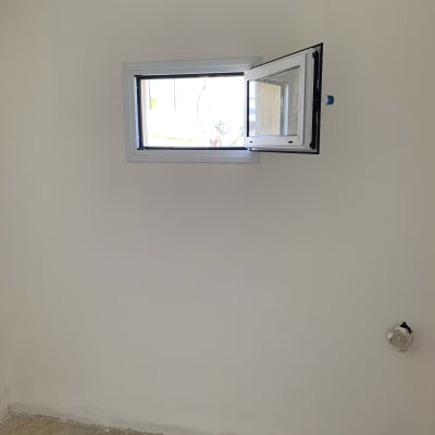 חלון אלומיניום קטן פתוח בקיר לבן