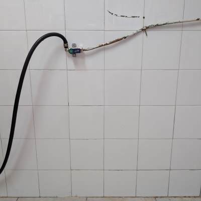 צינור מחובר לקיר עם אריחים לבנים