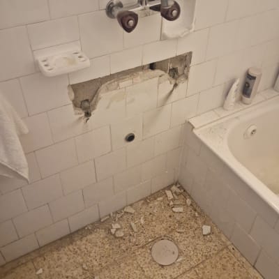 ברז מותקן על קיר עם אריחים שבורים