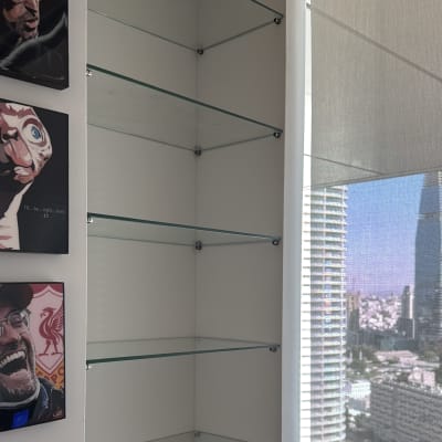 מדפי זכוכית מותקנים בפינת חדר ליד חלון גדול