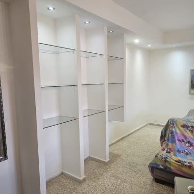 מדפי זכוכית מותקנים בקיר לבן עם תאורה שקועה