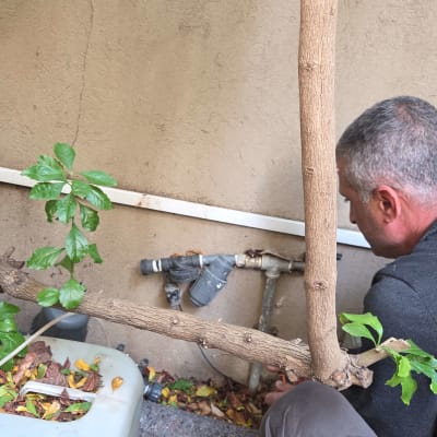 אדם עובד על צנרת מים ליד קיר חיצוני