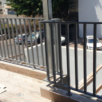 מעקה מתכת אפור על מרפסת עם רצפת עץ