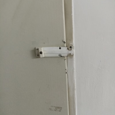 בריח דלת לבן עם ברגים על דלת עץ