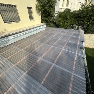 גג שקוף מותקן על מבנה עם עצים ברקע