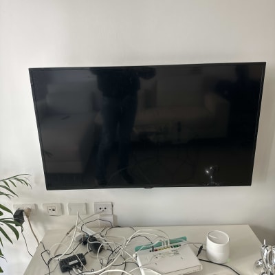 טלוויזיה תלויה על הקיר עם כבלים ומודם על השולחן