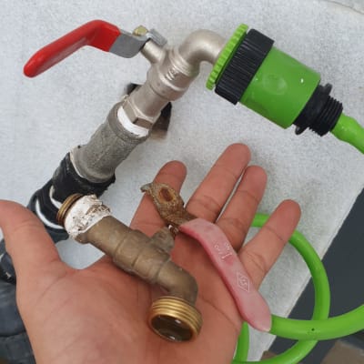 ברז מתכת עם ידית אדומה וצינור ירוק