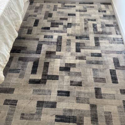 שטיח עם דפוס גיאומטרי וצינור ניקוי בתחתית התמונה