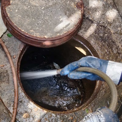 צינור שואב בתוך פתח ביוב עם כפפות עבודה