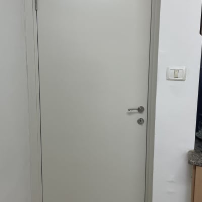 דלת לבנה עם ידית מתכת ומתג חשמל