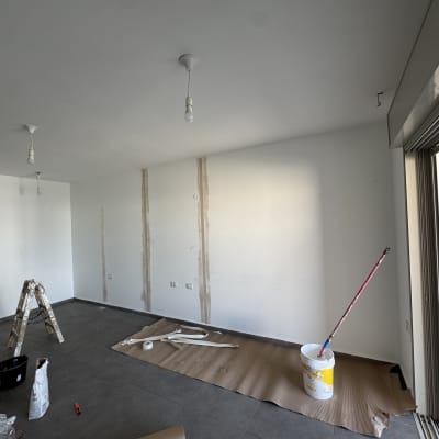 חדר עם קירות צבועים, סולם וכלי עבודה לצביעה