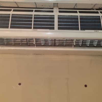 מזגן קיר עם תריסים פתוחים על קיר בהיר