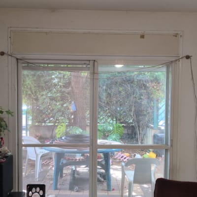 חלון עם תריסים סגורים וחוטים תלויים בצדדים