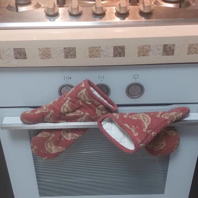 תנור גז עם כפתורים וכפפות מטבח על הידית