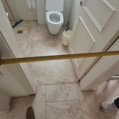 מדידת רוחב דלת עם סרט מדידה בחדר אמבטיה