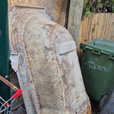 אמבטיה ישנה עם צינור ליד פח ירוק