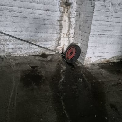 גלגל עם כבל ליד קיר בטון עם סימני רטיבות