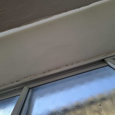 חלון עם מסגרת מתכת ותקרה עם סדקים